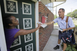 Ohio letter carrier Keith McVey hands the day's mail to Raina Washington as he makes his daily deliveries in Akron, Ohio on Friday, July 16, 2010. The veteran mailman has gained a reputation for three-times delivering people from life-threatening situations while on the job delivering mail. Last week he gave CPR to a man along his Akron route who wasn't breathing and whose lips were turning blue. (AP Photo/Amy Sancetta)